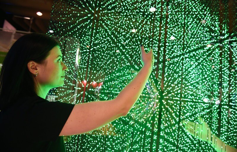 A person interacts with a display of lasers in a star-shaped pattern