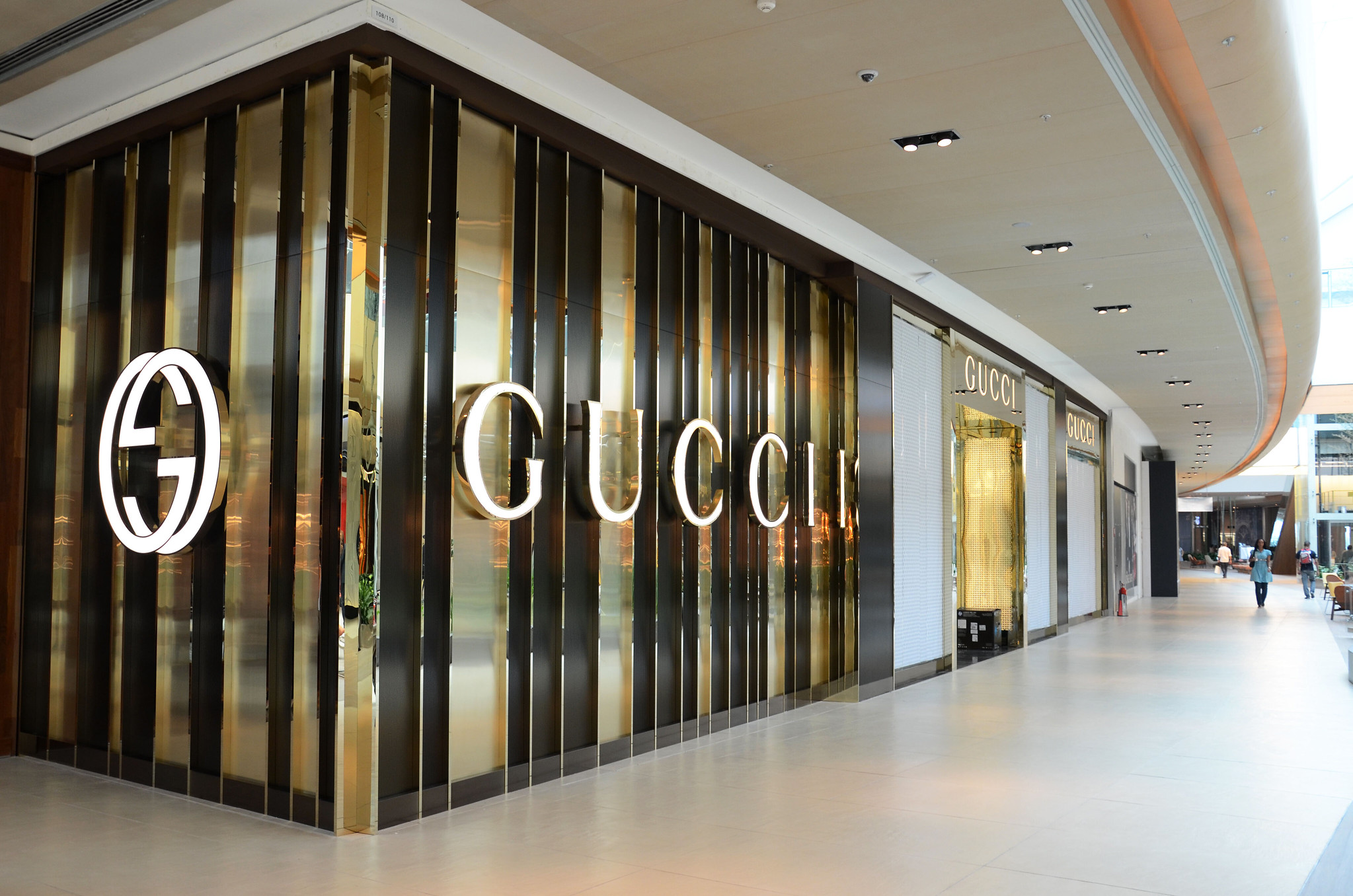 Interior of a shopping mall. A corner unit. The unit has glass walls with vertical stripes. One wall is emblazoned with 'Gucci' in large letters. The other has the Gucci logo (two interlocked capital Gs). Image: Alexandre Macieira/Riotur