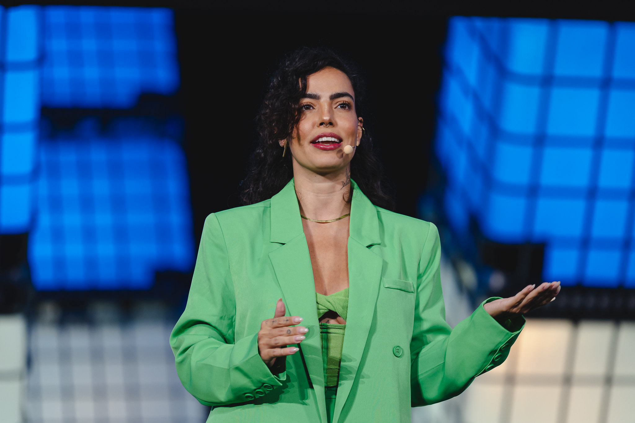 Photograph of a person (Laura Vicente, presenter at Globo) speaking onstage at Web Summit Rio. They are wearing a microphone and gesturing with their hands.